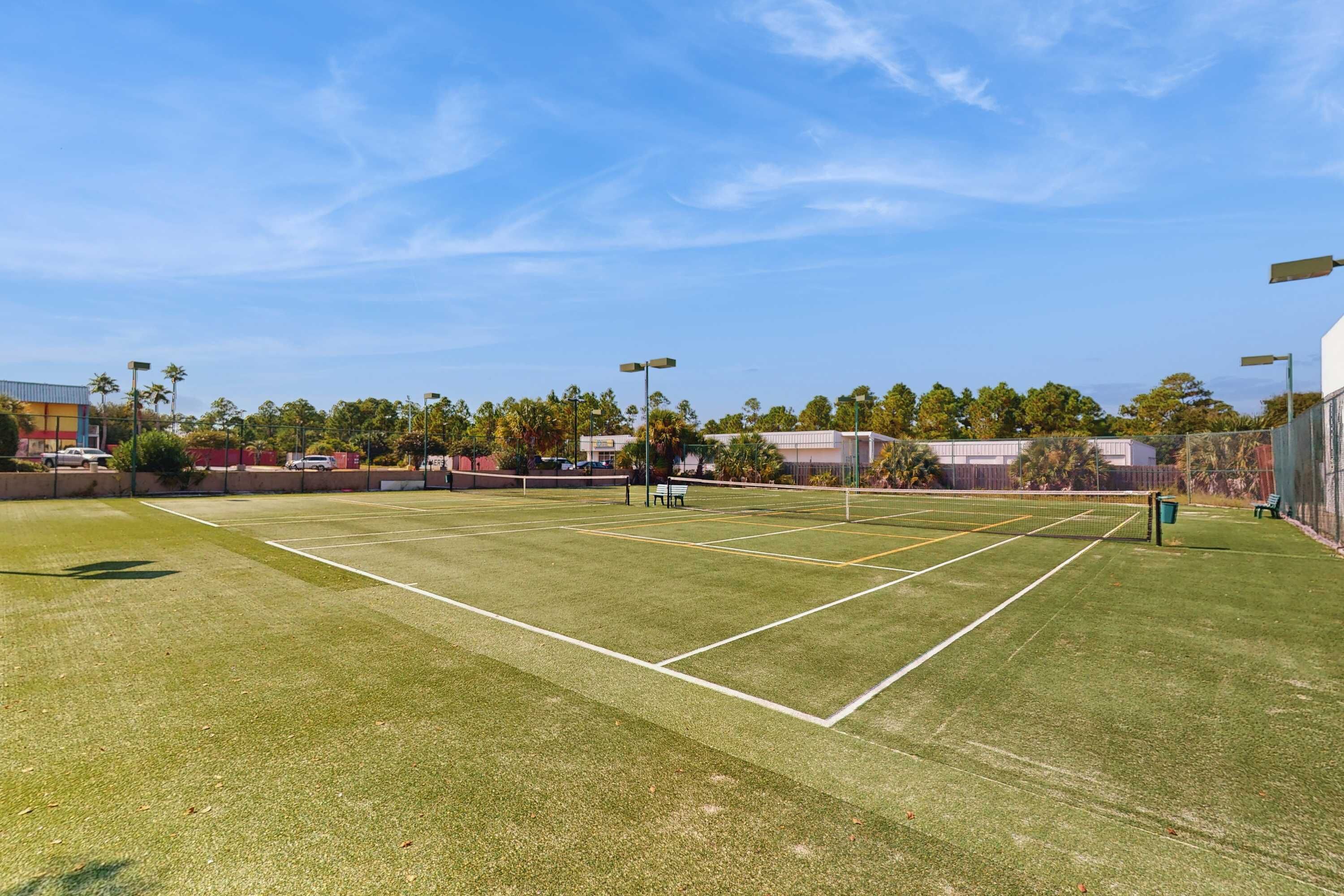 A tennis court with a net, surrounded by trees and buildings.