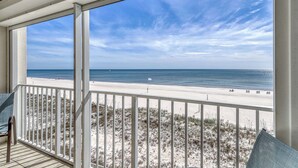 A balcony with a view of a beach and ocean. - Updated, Gulf front condo with beautiful views, shared pool, sauna, and hot tub (Orange Beach)