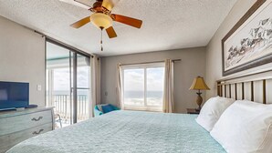 A hotel room with a bed, a ceiling fan, a television, a window with curtains, and a painting on the wall. - Updated, Gulf front condo with beautiful views, shared pool, sauna, and hot tub (Orange Beach)