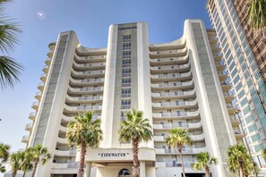 Un hôtel de grande hauteur doté de nombreux balcons, bordé de palmiers et dont la façade porte l’inscription « Tidewater ».