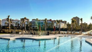 A swimming pool with lounge chairs and palm trees, surrounded by multi-story buildings. - Brand-new home near the beach with on-site pool, central AC, & washer,dryer (Orange Beach)