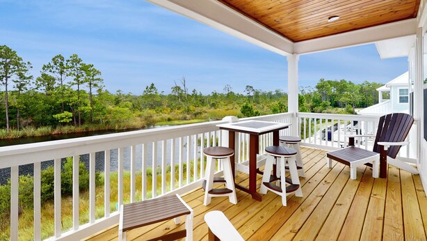 A wooden deck with white railings, a table, chairs, and a bench. - Brand-new home near the beach with on-site pool, central AC, & washer,dryer (Orange Beach)