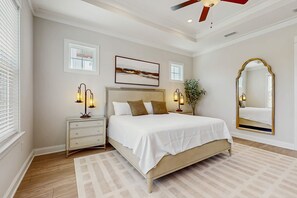 A bedroom with a bed, nightstands, a mirror, and a ceiling fan. - Modern beach house with porches, private washer and dryer- walk to the beach (Orange Beach)