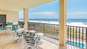 Ein Balkon mit Blick auf den Strand, weiße Stühle, ein kleiner Tisch und ein Pool.