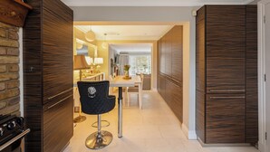 A modern kitchen with wooden cabinets, a dining area with a table and chairs, and a black chair with a decorative backrest.