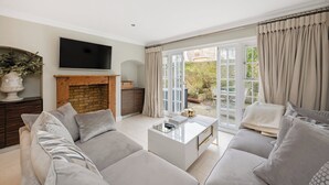 A living room with a sofa set, a coffee table, a flat-screen TV, and a fireplace.