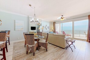 Een ruime woonkamer met een eettafel, stoelen, een bank en een balkon met uitzicht.