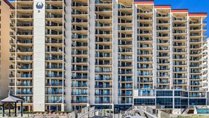 A multi-story hotel with balconies, a central atrium, and a pool area. - Renovated beachfront condo with balcony, central AC, pool, hot tub & tennis (Orange Beach)
