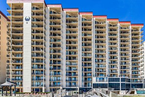 A multi-story hotel with balconies, a central atrium, and a pool area. - Renovated beachfront condo with balcony, central AC, pool, hot tub & tennis (Orange Beach)