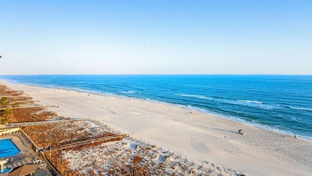 A beach view with a pool, beach chairs, and a lifeguard tower. - Renovated beachfront condo with balcony, central AC, pool, hot tub & tennis (Orange Beach)