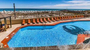 A swimming pool with a lifeguard stand, lounge chairs, and a view of the beach. - Renovated beachfront condo with balcony, central AC, pool, hot tub & tennis (Orange Beach)