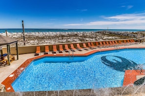 A swimming pool with a lifeguard stand, lounge chairs, and a view of the beach. - Renovated beachfront condo with balcony, central AC, pool, hot tub & tennis (Orange Beach)