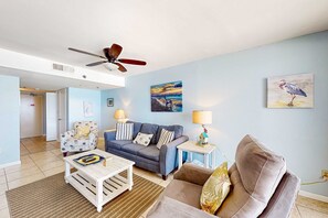 A living room with a sofa, a coffee table, a lamp, and a ceiling fan. - Phoenix II condo with Gulf views, shared pool, hot tub, sauna, tennis, & WiFi (Orange Beach)