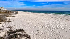 En strand med en träpromenad, sandstrand och hav.
