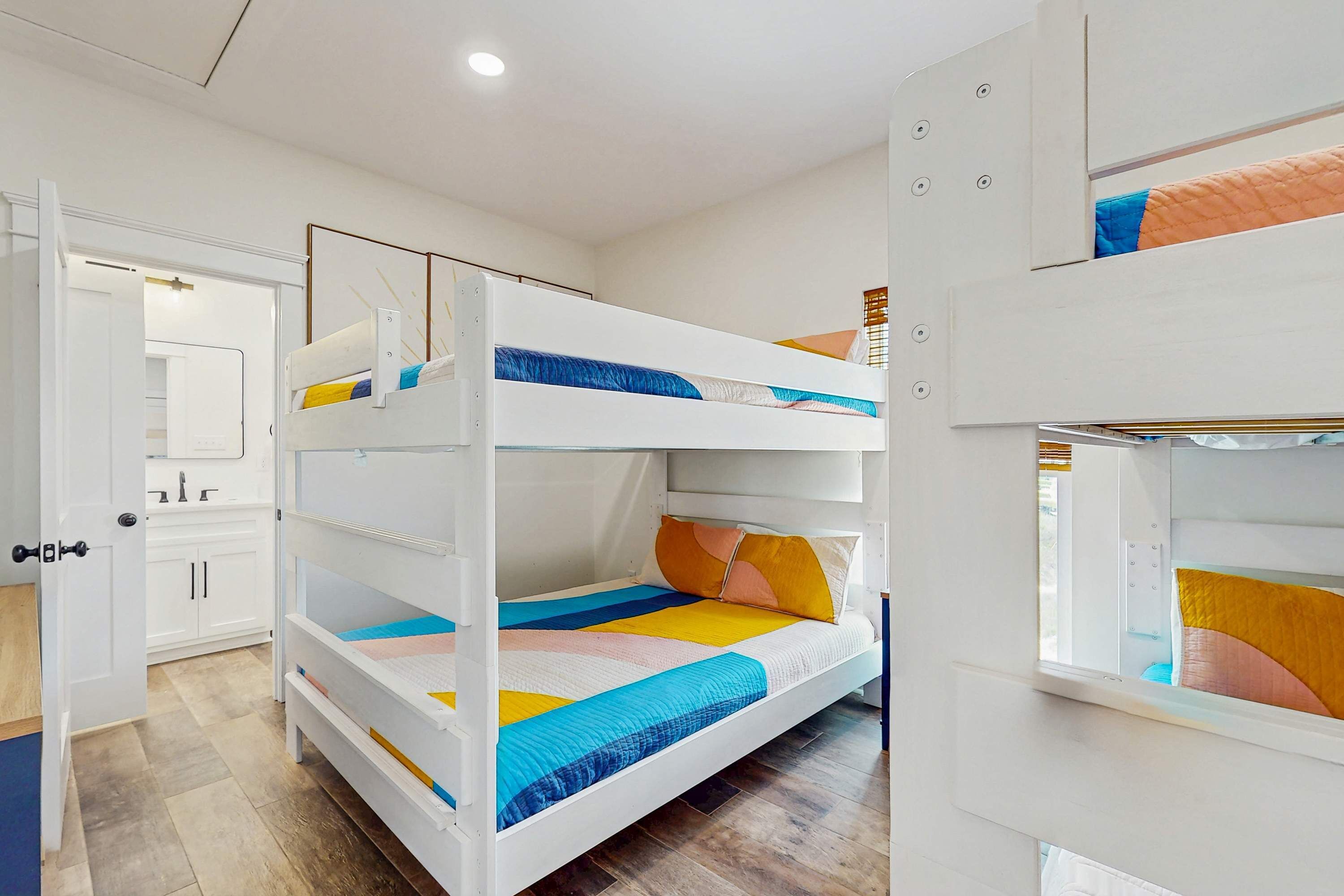 A bunk bed room with a white door, a mirror, and a window.