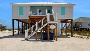 Ein Strandhaus mit Holzterrasse, einer Treppe und einem Schild mit der Aufschrift 'Feelin' Tip Sea'.