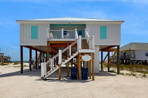A beach house with a wooden deck, a staircase, and a sign that reads 'Feelin' Tip Sea.' - Gulf-Front Oasis: Rooftop Heated Pool, Elevator & Dog-Friendly! (Dauphin Island)