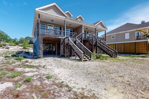 A two-story house with a balcony, a staircase, and a wooden deck. - Bright duplex with two full kitchens, large decks, and private washer/dryers (Dauphin Island)