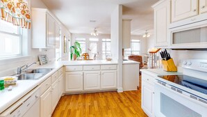 Una cocina moderna con armarios blancos, suelo de madera y una isla central.