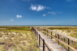 A wooden boardwalk leading to a beach with a clear sky.