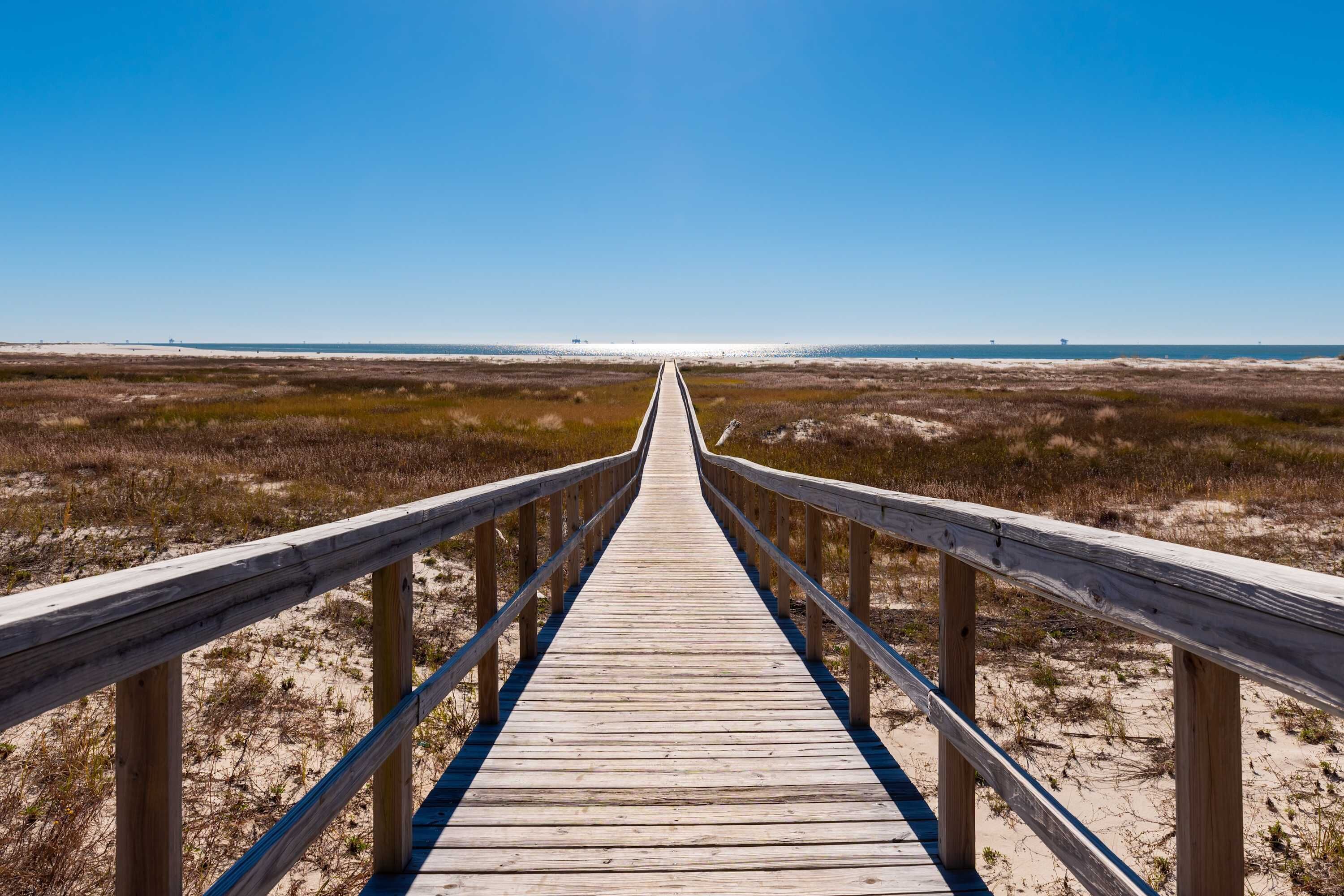 Une promenade en bois menant à une plage.