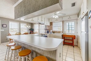 A kitchen with a central island, white cabinets, and a ceiling fan. - Dog-Friendly Bayfront Getaway w/ Two Kitchens, Free WiFi, & a Great Location! (Dauphin Island)
