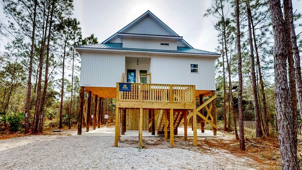 A two-story wooden cabin with a balcony, surrounded by pine trees. - Peaceful hideaway with modern interior & spacious balcony - adjacent to the dune (Dauphin Island)