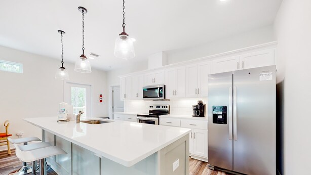 A modern kitchen with white cabinets, stainless steel appliances, and a large island with bar stools.