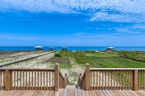 A wooden deck leading to beach huts with a clear view of the ocean. - Idyllic, dog-friendly Bay Front Island home with pool, Gulf view & large decks (Dauphin Island)