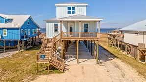A beachfront property with a central wooden structure, elevated walkways, and a clear view of the ocean. - Idyllic, dog-friendly Bay Front Island home with pool, Gulf view & large decks (Dauphin Island)