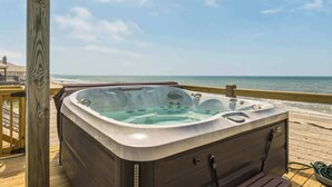 Een hottub op een houten terras met uitzicht op de oceaan.
