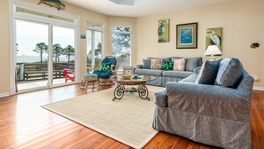 A living room with a sofa, armchairs, a coffee table, and artwork on the walls. - Tan Lanes! Cozy, affordable and direct access to the beach. (Dauphin Island)