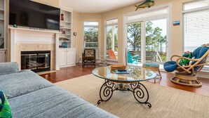 A living room with a fireplace, television, and seating area. - Tan Lanes! Cozy, affordable and direct access to the beach. (Dauphin Island)