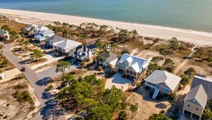 An aerial view of a coastal residential area with houses, a beach, and a clear sky. - Tan Lanes! Cozy, affordable and direct access to the beach. (Dauphin Island)