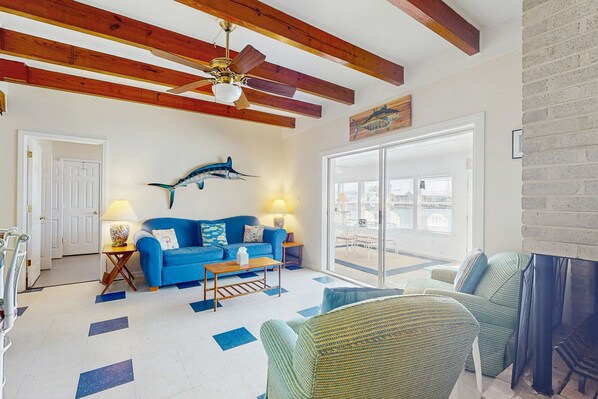 Ein Wohnzimmer mit einem blauen Sofa, einem Holztisch und einem Deckenventilator.