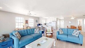 A spacious living area with two blue sofas, a white coffee table, and a kitchen in the background. - Welcoming home with WiFi, gulf views & spacious deck - steps to the beach (Dauphin Island)