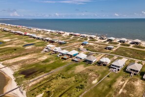 An aerial view of a coastal residential area with houses, a beach, and a bridge. - Bayfront home with beach access & breathtaking water views - dog-friendly (Dauphin Island)