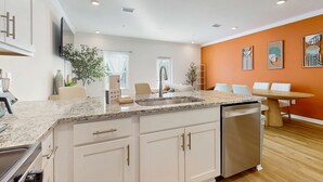 A modern kitchen with white cabinets, a granite countertop, and a dishwasher. - Dog friendly home near the Wharf with internet and free parking (Orange Beach)