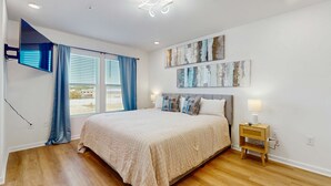 A bedroom with a large bed, a TV mounted on the wall, and artwork above the bed. - Dog friendly home near the Wharf with internet and free parking (Orange Beach)