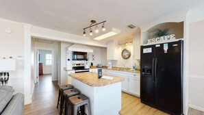 Una cocina moderna con una isla central, electrodomésticos de acero inoxidable y un refrigerador negro.