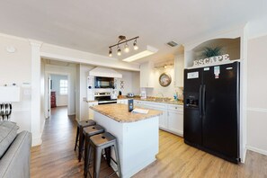 A modern kitchen with a central island, stainless steel appliances, and a black refrigerator. - Dog-friendly home with sound-side deck, full kitchen, & fantastic views (Dauphin Island)