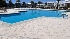 En swimmingpool med solstolar och en stenlagd uteplats.