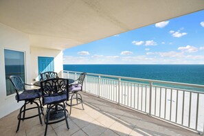 A balcony with a table and chairs, a view of the sea, and a white railing. - Upscale beachfront retreat w/private balcony, resort pool, sauna, & beach access (Orange Beach)