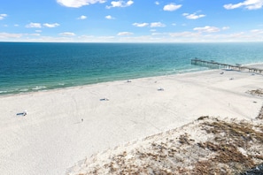 A beach with a pier extending into the ocean, sandy beach, and clear blue sky. - Upscale beachfront retreat w/private balcony, resort pool, sauna, & beach access (Orange Beach)