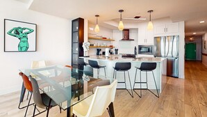 Una cocina moderna con una isla central, taburetes de bar e iluminación colgante.
