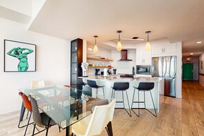 A modern kitchen with a central island, bar stools, and pendant lighting. - Gulf front condo with direct beach access, resort amenities, private W&D, WiFi (Orange Beach)