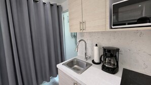 A modern kitchen with a stainless steel sink, a coffee maker, and a microwave. - Tierra Serena - Private Nature Retreat (Rincón)