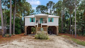 Une maison à deux étages avec un porche, entourée d’arbres.