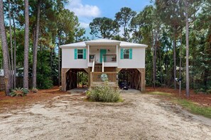 A two-story house with a porch, surrounded by trees. - Island Home With Spacious Deck, Lower Patio, Free WiFi, & Beach Access Nearby (Dauphin Island)