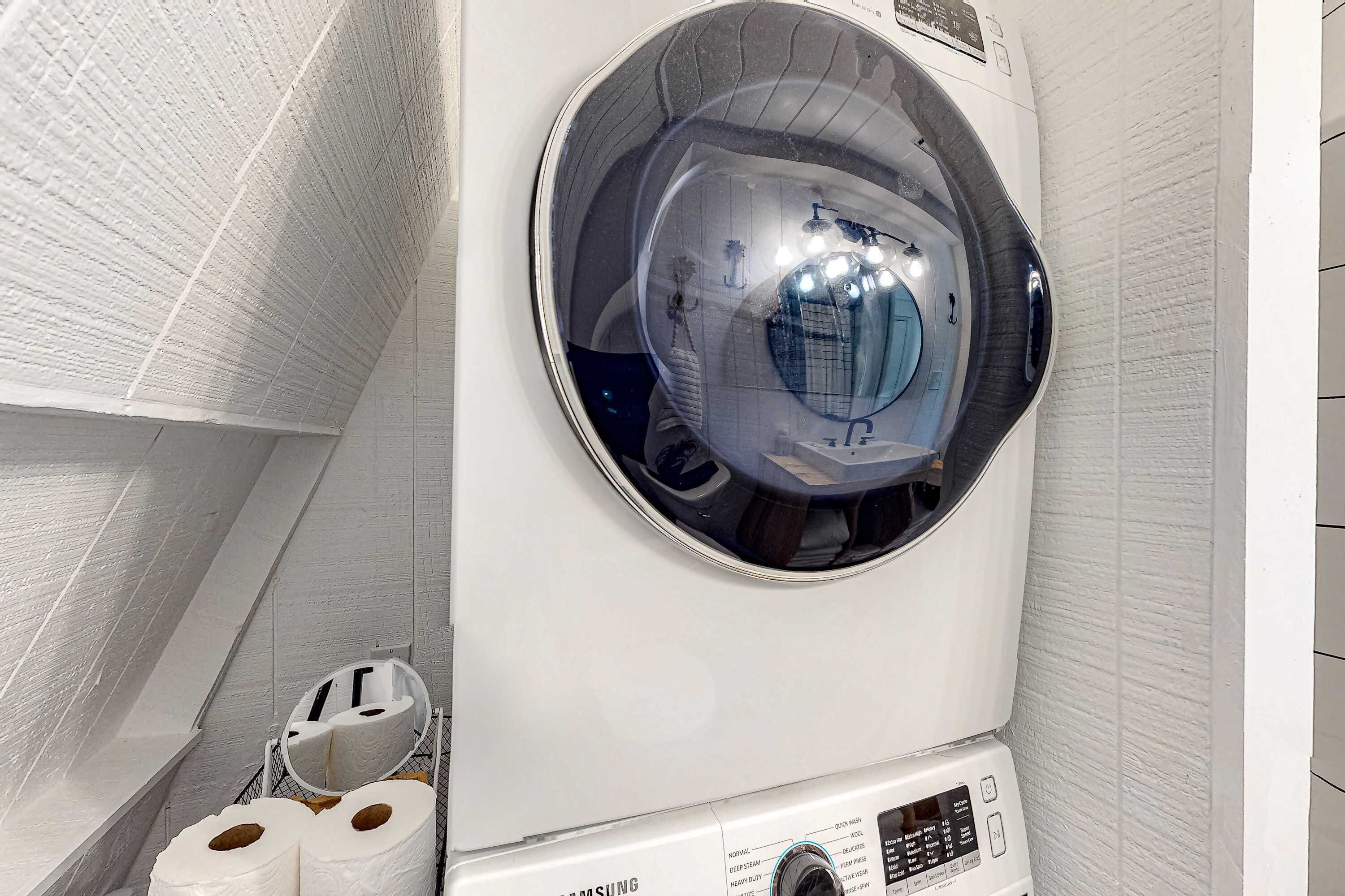 A Samsung washing machine in a bathroom with white walls and a tiled floor.
